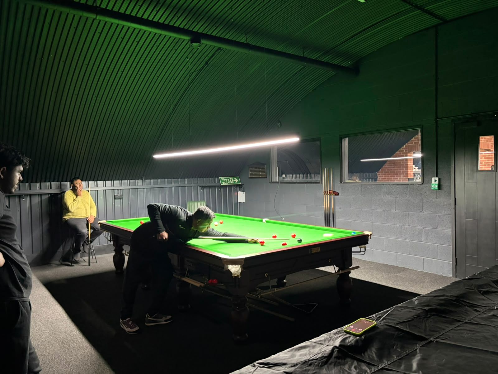 Players around a snooker table during a game at the club.