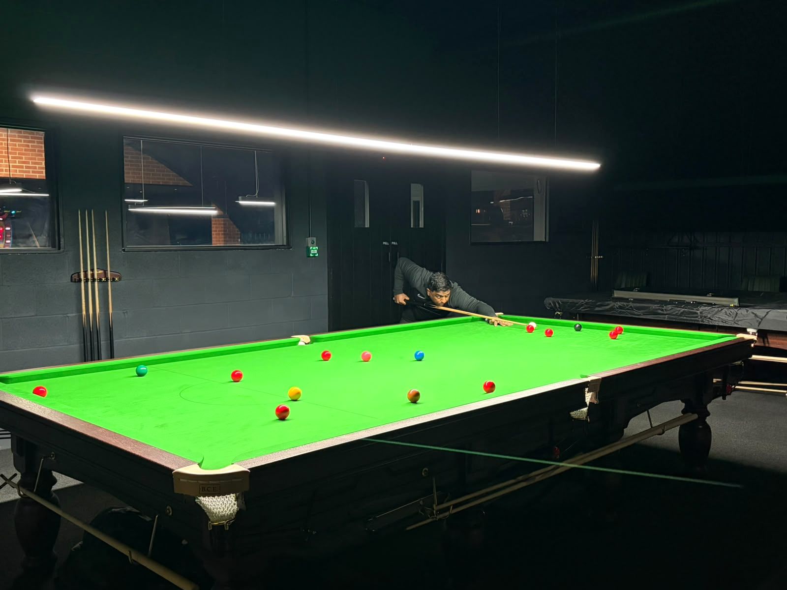 A player lining up a shot on one of the club's green-baize snooker tables.